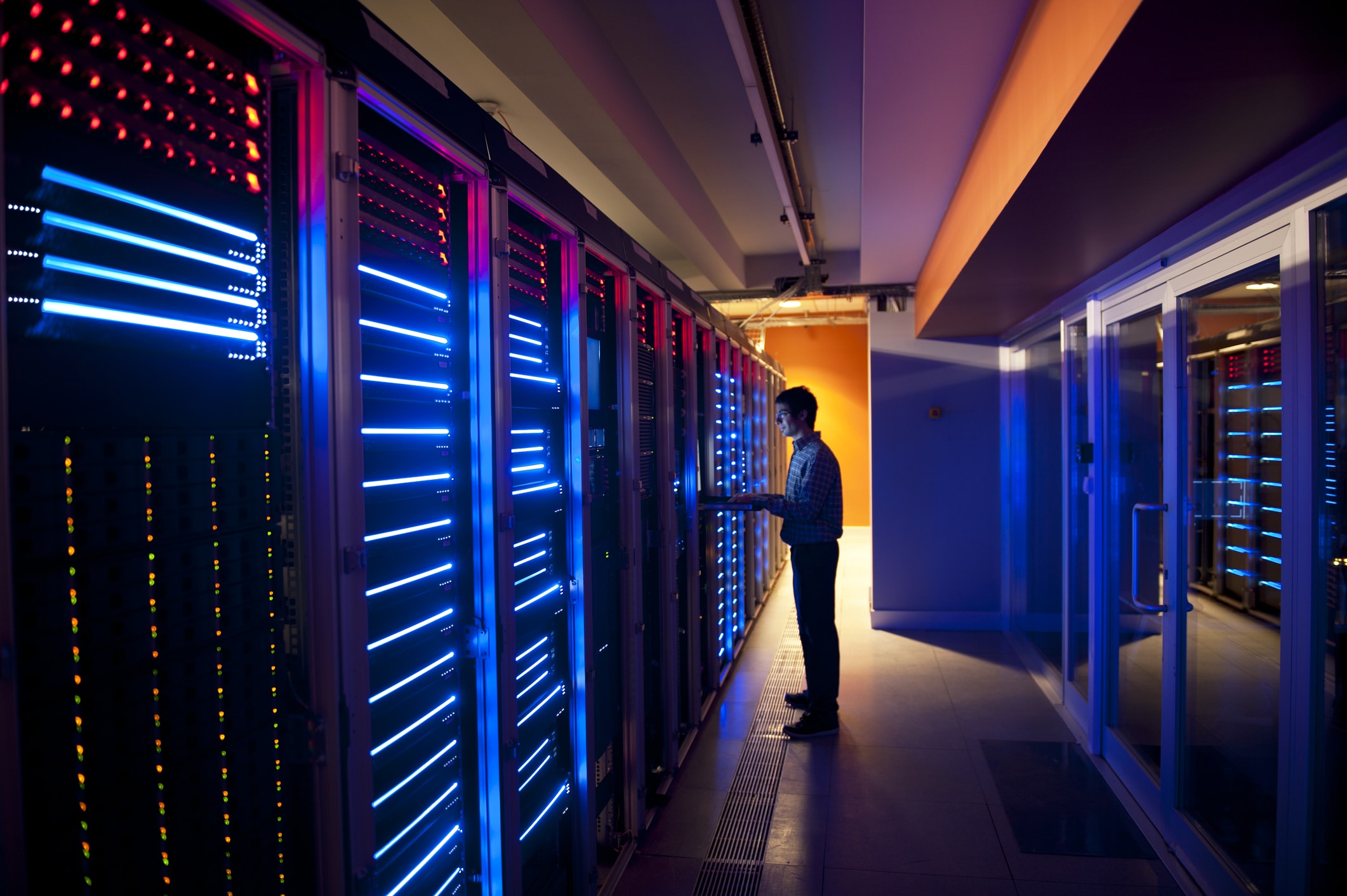 Person interacting with illuminated server racks. IT Infrastructure Solutions